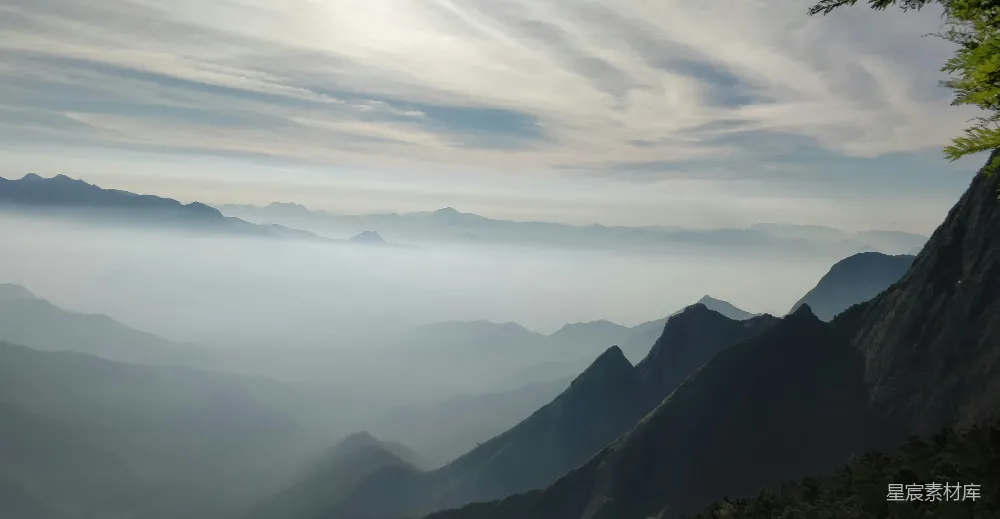 这张图片展示了一片云海中被山峦环绕的景象，远处的山峰隐约可见，近处的山峰则被云雾笼罩，给人一种宁静而神秘的感觉。这种场景通常出现在旅游摄影中，用来展现大自然的壮丽与宁静。