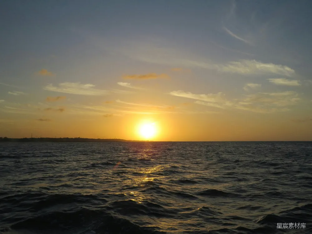 夕阳缓缓落下，金色的光芒洒在波光粼粼的海面上，形成一幅美丽的自然画卷。天空中散布着几朵轻盈的云彩，海浪轻轻拍打着海岸，带来一丝宁静与祥和。这幅画面适合用作自然风光的背景或旅行记录。