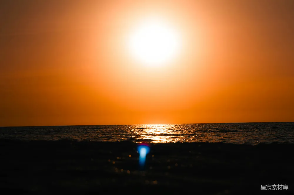 这幅图片展示了一片宁静的海景，夕阳的余晖洒在海面上，波光粼粼。天空被染成了温暖的橙色，给人一种宁静而祥和的感觉。适合用作自然风光、旅行摄影或表达宁静心情的主题图片。