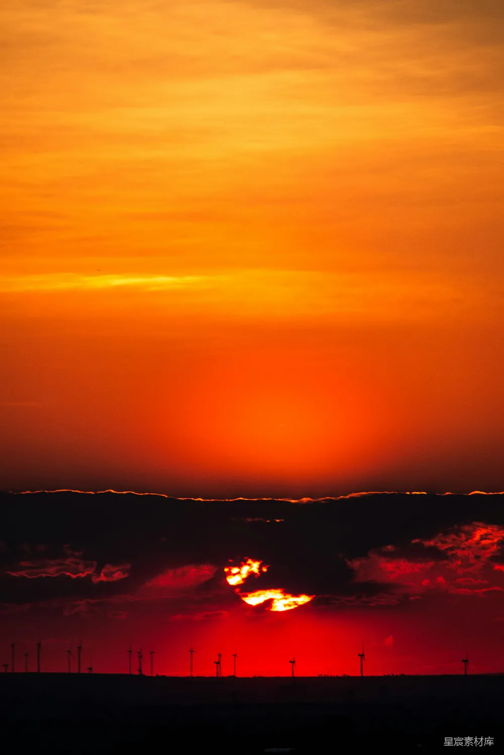 夕阳的余晖洒在风车群上，橙红色的天空与黑色的剪影形成鲜明对比，营造出一种宁静而美丽的自然景象。适合用作自然风光、宁静生活或环保主题的背景图。