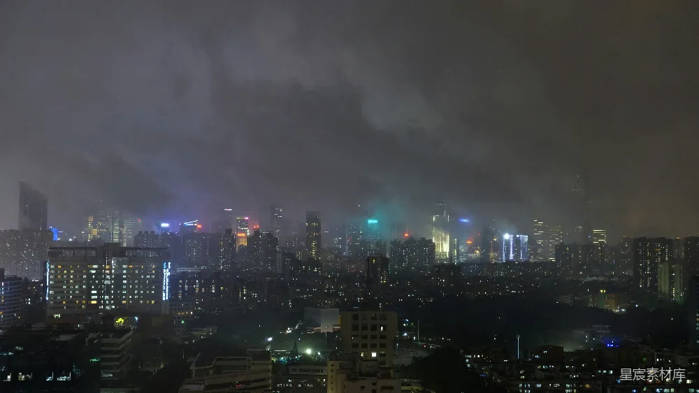 这张图片展示了夜晚的城市景象，高楼大厦在灯光的照耀下显得格外醒目。远处的天空中弥漫着浓密的雾气，使得城市的轮廓变得模糊，增添了一种神秘和宁静的氛围。这种场景适合用于城市纪录片、城市风光摄影集或夜间城市生活的主题展示。