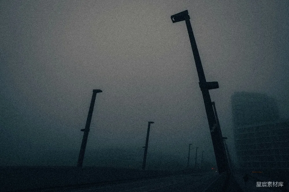 这张图片展示了一条街道上的路灯在雾中若隐若现的景象。路灯在雾气的笼罩下显得有些朦胧，营造出一种宁静而神秘的氛围。这种场景通常适合用于表现城市的夜晚，尤其是雾中的城市景观，给人一种静谧而略带孤独的感觉。