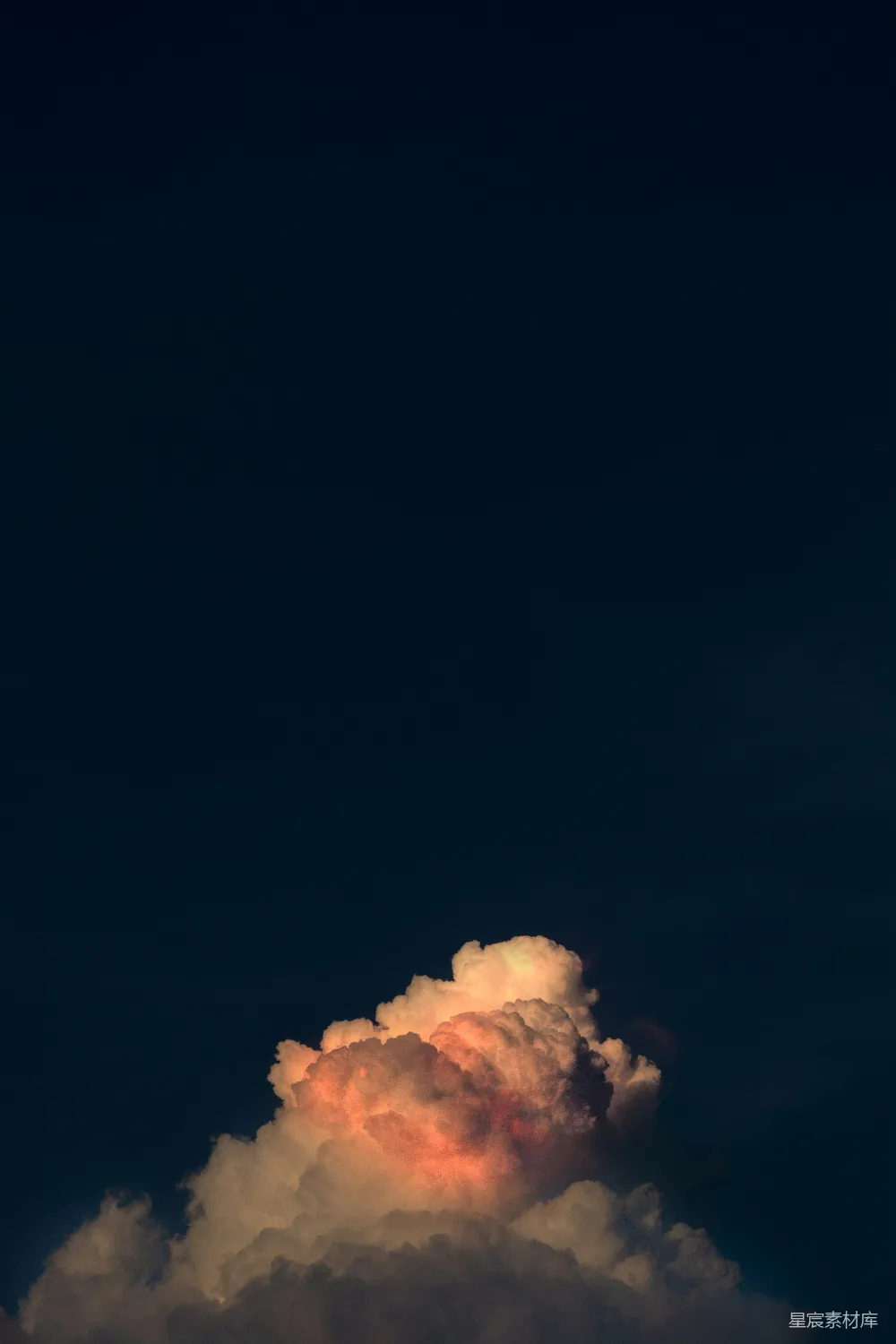 这张图片展示了一个宁静的夜空场景，天空中漂浮着一朵被夕阳染成橙红色的云朵，仿佛是火烧云。云朵的形态独特，给人一种宁静而梦幻的感觉，适合用作壁纸或用于表达自然宁静的主题。