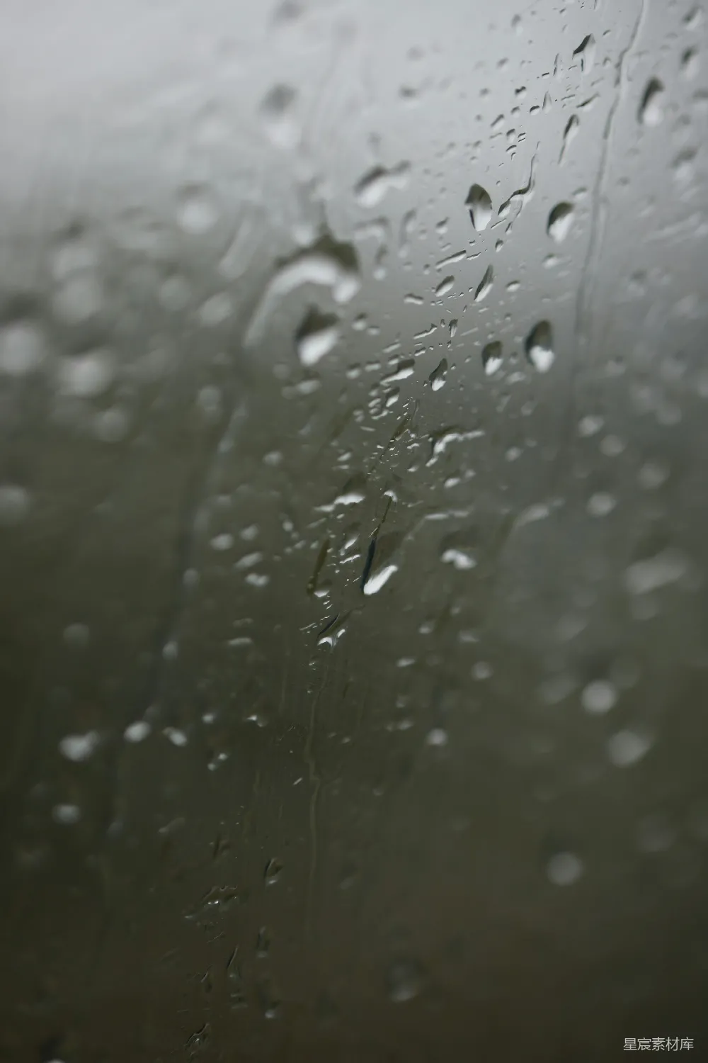 这张图片展示了玻璃上凝结的雨滴，它们在光线的照射下显得晶莹剔透，仿佛在诉说着秋天的雨季。背景模糊，突出了雨滴的细节，营造出一种静谧而富有诗意的氛围。适合用于表现秋天、雨季或静谧氛围的主题。