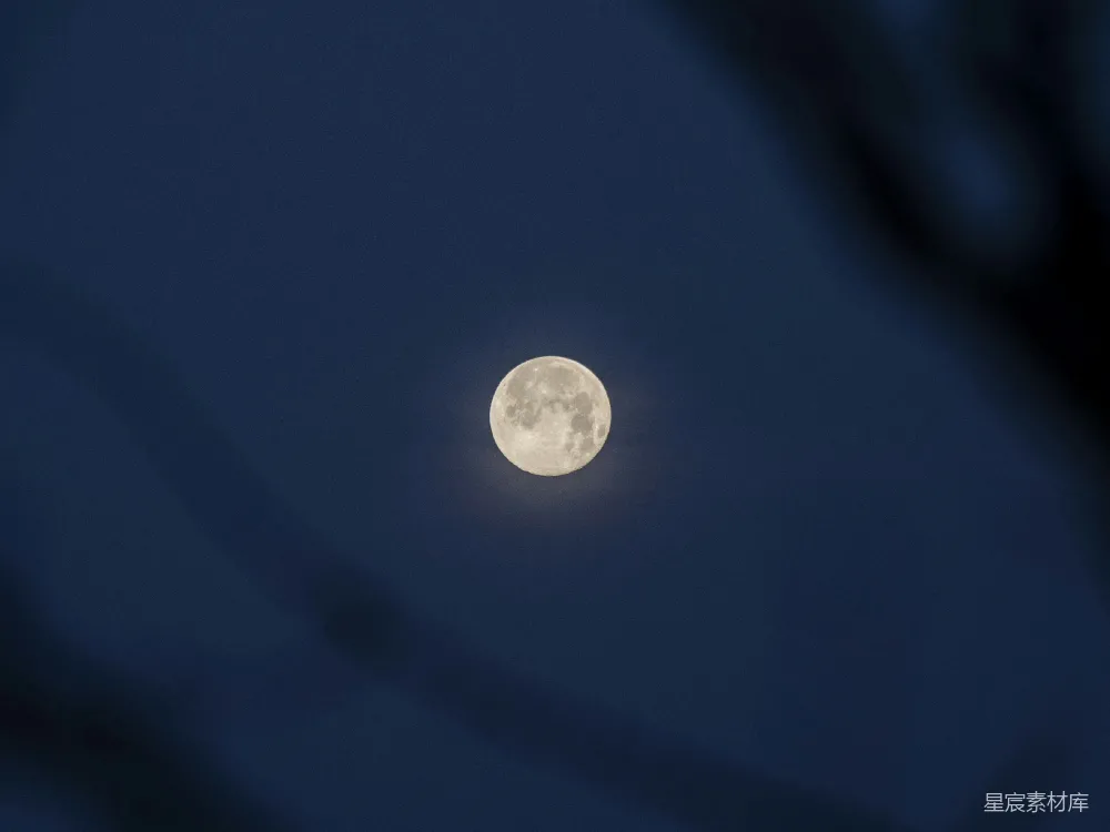 这张图片展示了夜空中明亮的满月。满月位于画面中心，周围是深邃的蓝色夜空，月亮的细节清晰可见，给人一种宁静和神秘的感觉。适合用于自然风光、摄影展示或冥想场景。