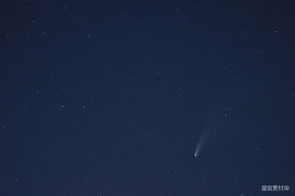 这张图片展示了一个宁静的夜空，背景中点缀着无数闪烁的星星。在画面的右下角，一颗彗星清晰可见，其长长的尾巴在黑暗的夜空中格外显眼。这种场景适合用于天文爱好者、自然风光以及宁静氛围的图片。