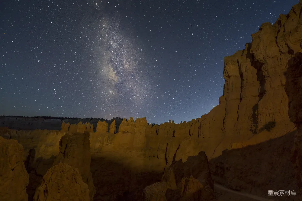 这张图片展示了一个令人惊叹的夜景场景，银河清晰可见，点缀在深邃的夜空中。岩石形成独特的地貌，仿佛在诉说着古老的地质故事。整个画面充满了宁静与神秘，适合用作自然风光、摄影或旅行相关的背景图片。
