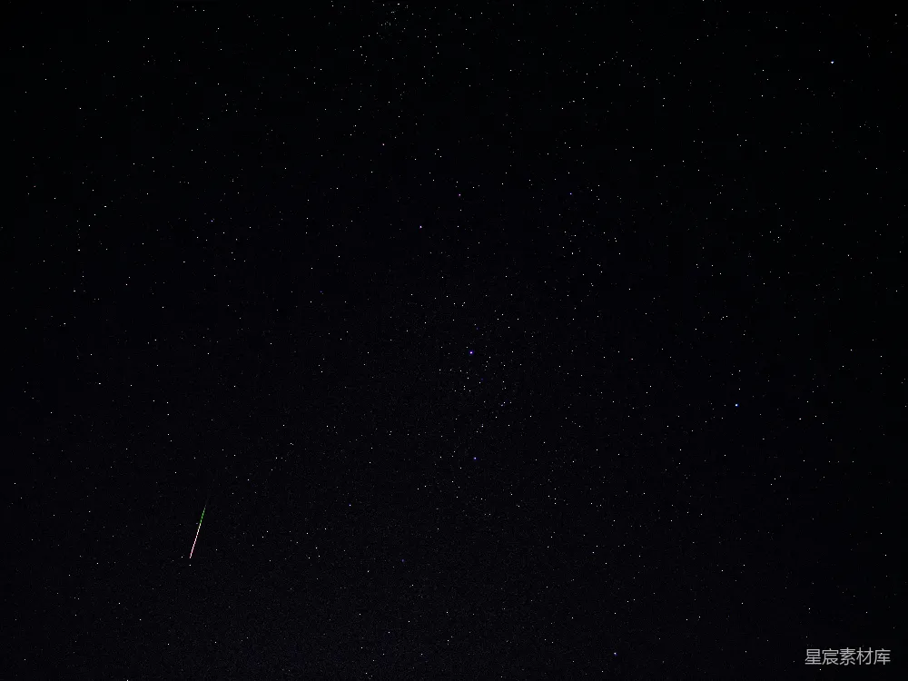 这张图片展示了一个流星在夜空中划过的场景。黑暗的夜空布满了星星，流星的尾巴在夜空中留下了长长的光迹，营造出一种宁静而神秘的氛围。这张图片适合用于天文摄影、夜景摄影或自然风光的展示。