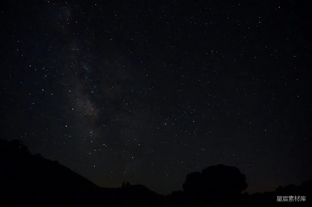 这张图片展示了夜空中繁星点点的银河，银河横跨夜空，星星闪烁，地平线处有树木和岩石的剪影。整体画面宁静而神秘，适合用作自然风光、天文摄影或静谧夜晚的背景素材。