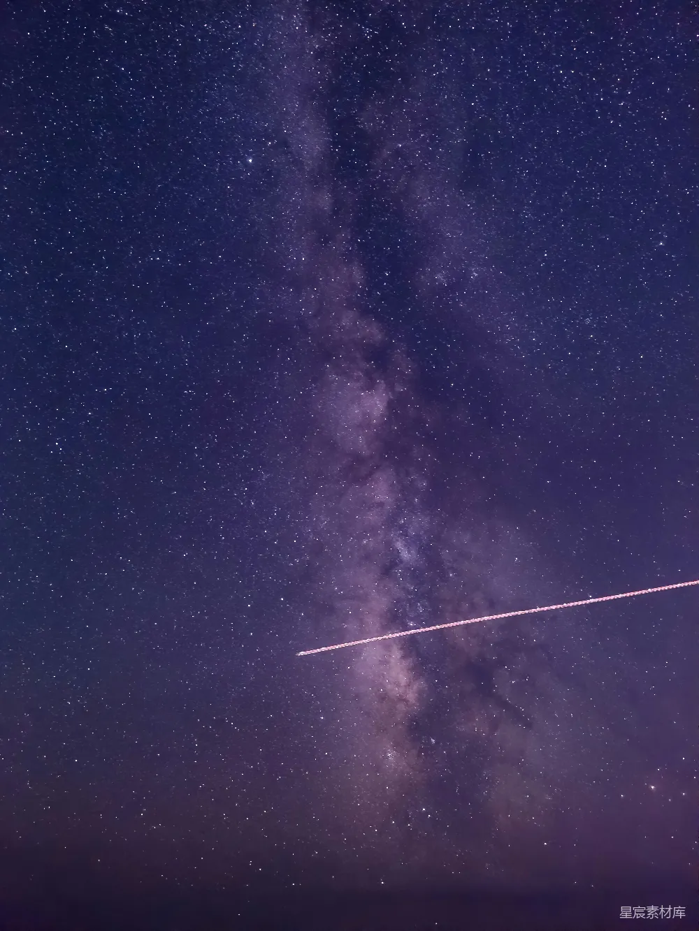 这张图片展示了夜空中璀璨的银河与划过的流星，背景是深邃的夜空，点缀着无数的星星。银河的中心部分呈现出粉紫色，与周围的黑色背景形成鲜明对比，而流星则留下了长长的光轨，增添了画面的动感。这幅图片非常适合用于展示自然美景和宇宙探索的主题。