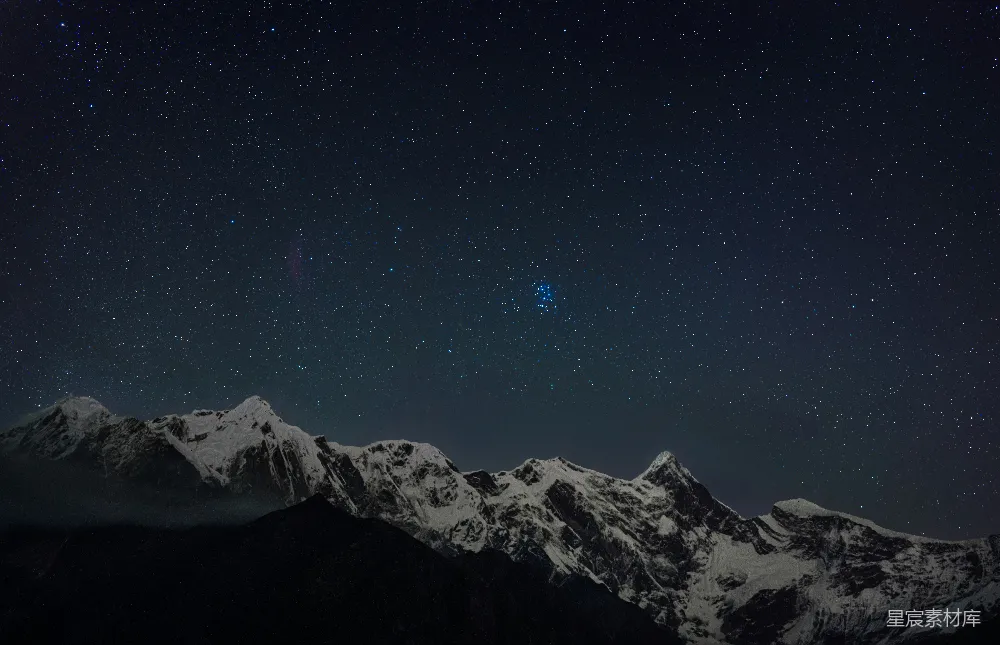 这张图片展示了在雪山下宁静的夜晚，繁星点缀的星空。雪山的轮廓在夜色中显得格外清晰，仿佛在诉说着大自然的壮丽与宁静。这幅画面适合用作自然风光的背景，或者用作冥想和放松的视觉元素。