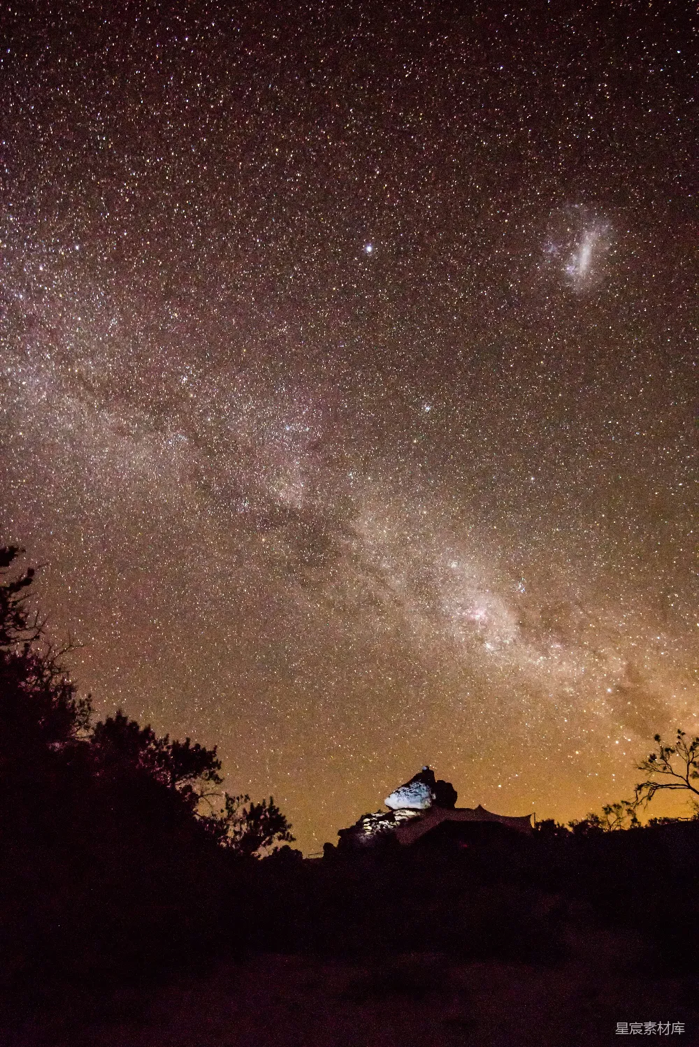 这张图片展示了夜空下的一顶帐篷，星星点点的夜空充满了神秘与美丽，地面上的帐篷在夜色中显得格外静谧。这张照片适合用于自然风光、露营、夜间摄影等场景，传达出一种宁静、神秘的氛围。
