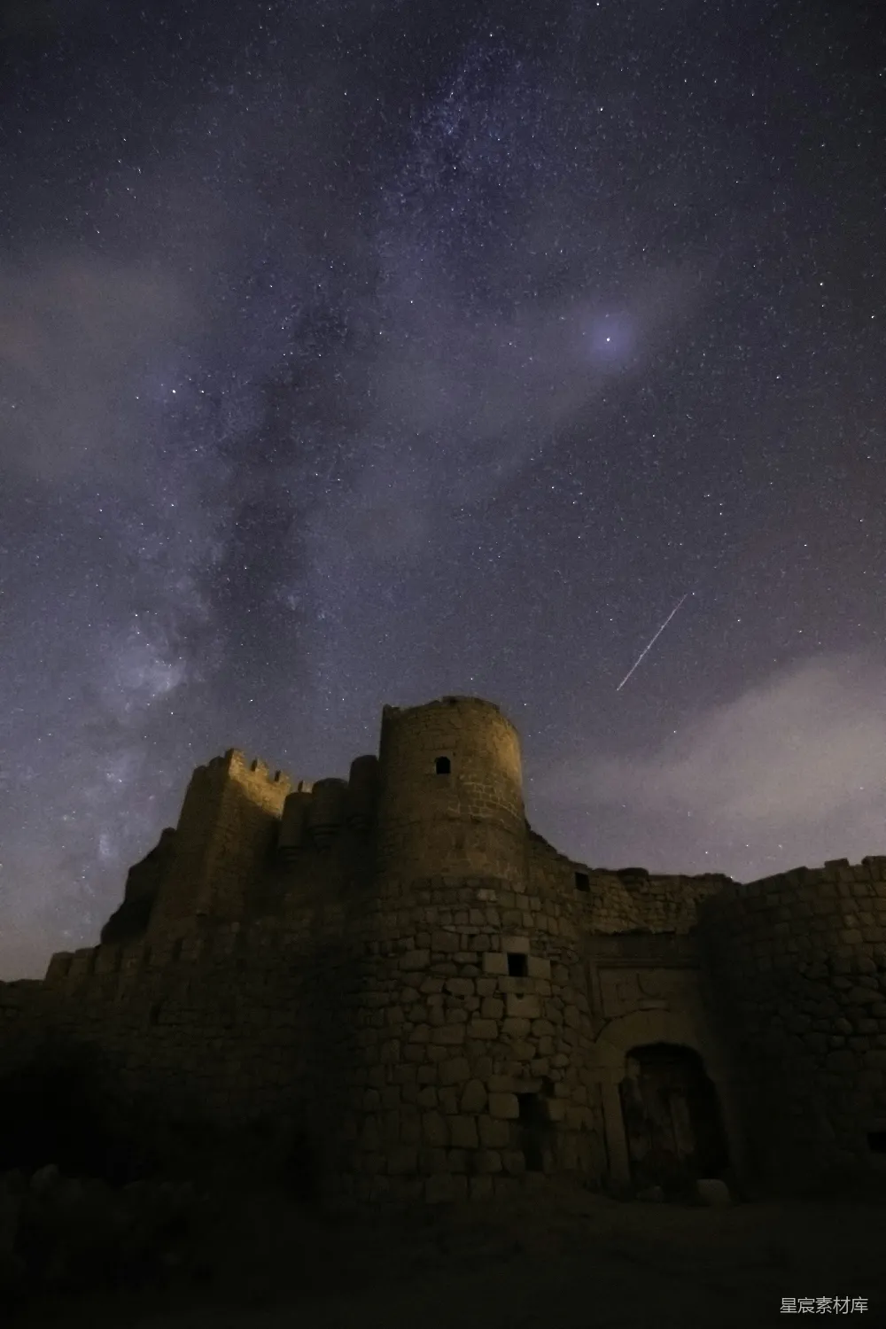 古堡在夜色中显得庄严而神秘，银河横跨夜空，流星划过，营造出一种宁静而壮丽的氛围。这张照片不仅展示了历史建筑的美丽，还捕捉到了自然与人文的和谐之美。适合用作历史、自然、摄影等主题的背景图片。