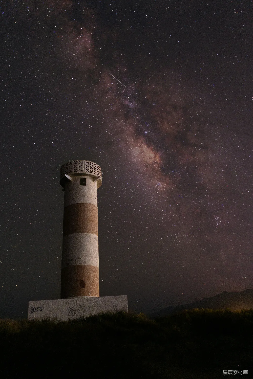 图片展示了一座孤独的塔在星空下，银河横跨夜空，星星点点，营造出一种宁静而神秘的氛围。塔身古朴，与璀璨的星空形成鲜明对比，适合用作探索自然美景、天文爱好者的背景图。