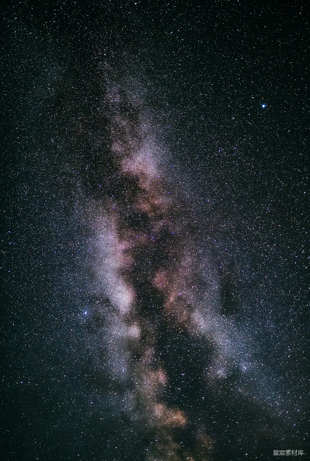 这张图片展示了一个宁静的夜空场景，其中充满了无数闪烁的星星和银河的壮观景象。银河的中心部分呈现出浓密的星云状，而周围的星星则显得更加分散和明亮。整个画面给人一种深邃、神秘且宁静的感觉，非常适合用于展现宇宙的浩瀚和自然的美丽。