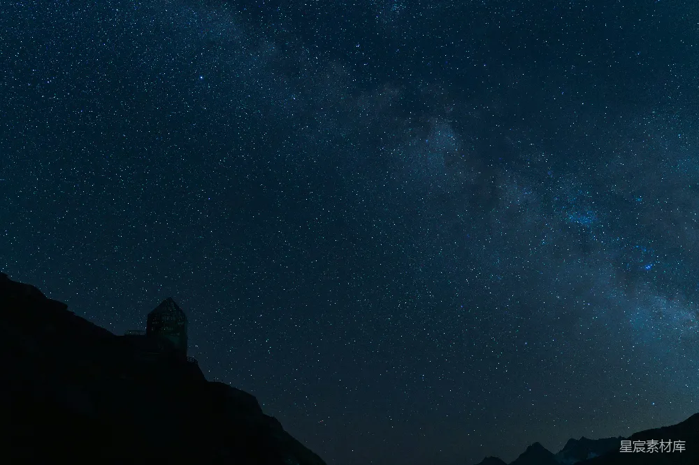 这张图片展示了一个位于山巅的观测站，周围是浩瀚的星空。夜晚的天空布满了无数的星星，银河清晰可见，营造出一种宁静而神秘的氛围。适合用于天文爱好者或自然风光的展示。