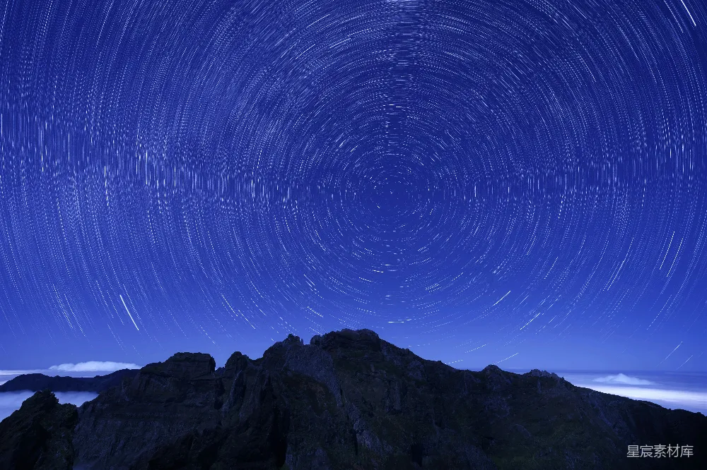 这张图片展示了在长曝光拍摄下，星空呈现出的美丽星轨效果。山峰在前景中显得雄伟，背景的夜空则被星星的轨迹填满，营造出一种宁静而神秘的氛围。适合用作自然风光、摄影技巧或夜间场景的背景素材。