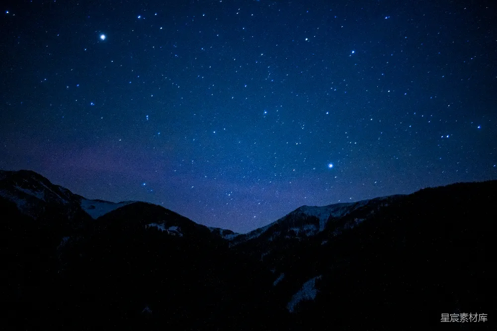 这张图片展示了一片宁静的夜空，无数星星点缀其间，下方是连绵起伏的山脉，山峦在黑暗中若隐若现，呈现出一种神秘而宁静的氛围。这种场景适合用作自然风光的背景，或是在表达宁静、平和心情时的配图。
