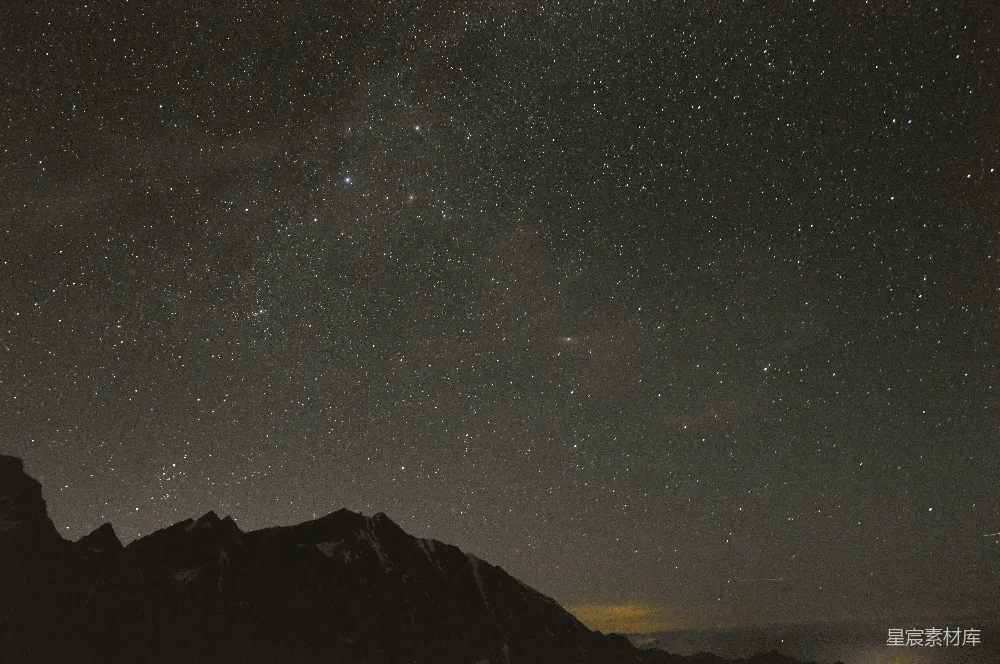 这张图片展示了夜空中繁星点点的美丽景象，山脉的剪影在星空下显得格外清晰。深邃的天空与地平线的交界处，微弱的光晕增添了画面的层次感，营造出一种宁静而神秘的氛围。适合用作自然风光、星空摄影或旅行主题的背景素材。