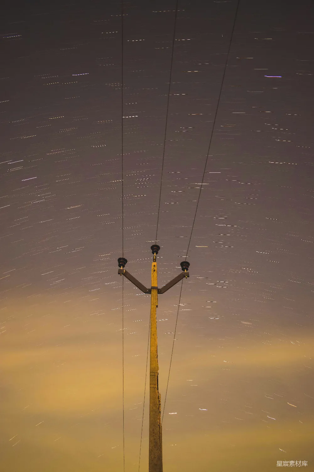 这张图片展示了一根电线杆在星空下的景象。夜空中星星点点，仿佛银河倾泻而下，与地面上的电线杆形成鲜明对比。这幅照片不仅展现了自然与城市景观的和谐共存，还传递出宁静而神秘的氛围。