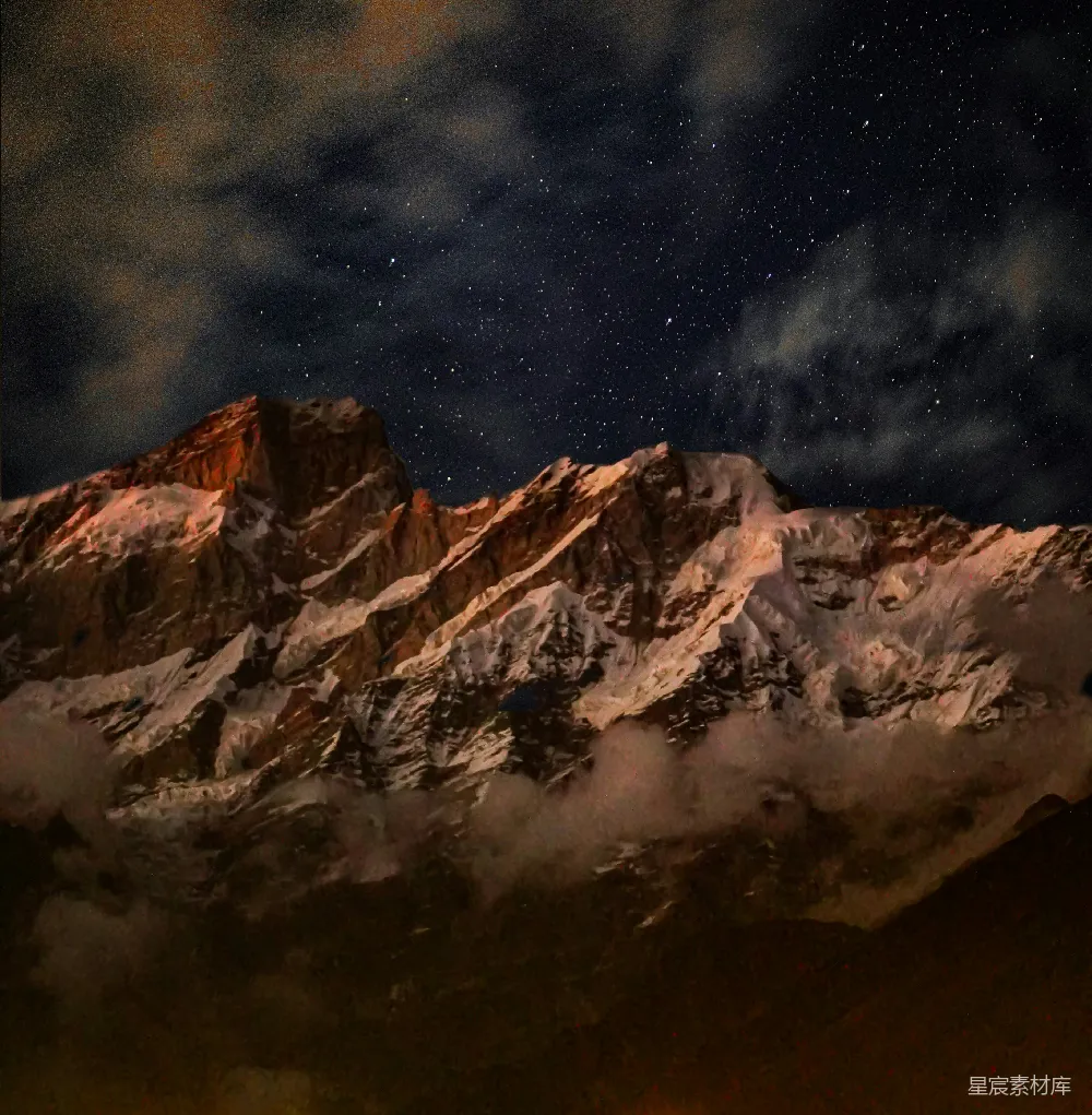 这张图片展示了夜晚的雪山景象，山峰在月光和星光的照射下显得格外壮丽，山脚下覆盖着薄雾，给人一种宁静而神秘的感觉。背景的星空点缀着无数的星星，与地面上的雪山形成鲜明对比，营造出一种宁静而又壮丽的自然景象。适合用作自然风光、旅游宣传、户外探险等