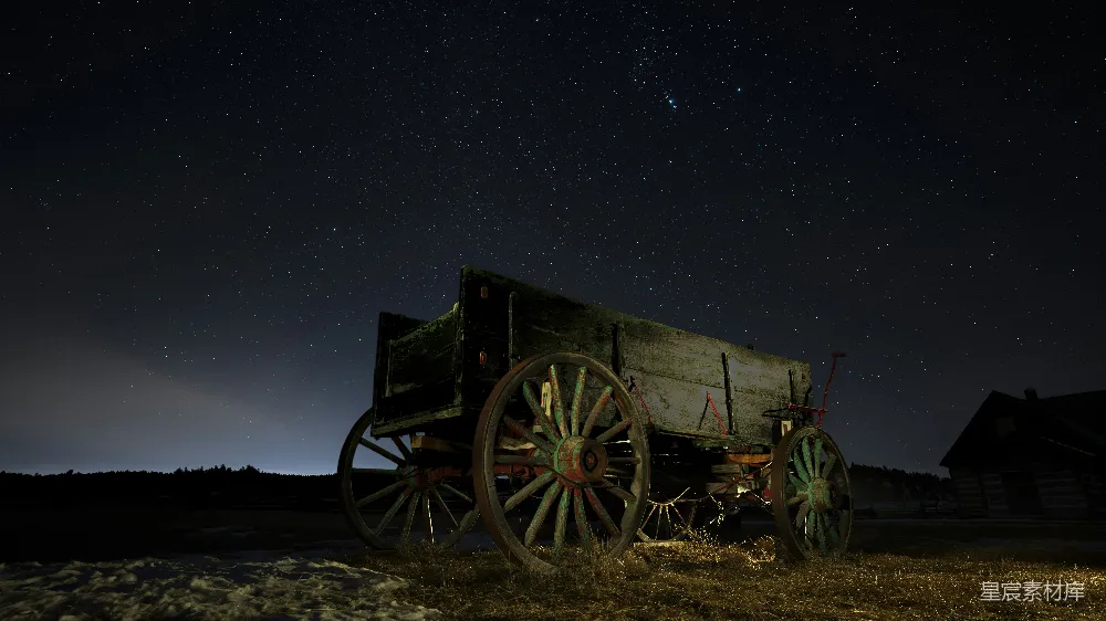 夜空中繁星点点，古色古香的马车静静地停在田间，仿佛诉说着往昔的故事。这幅画面结合了乡村的宁静与自然的壮丽，营造出一种怀旧而神秘的氛围。适合用作乡村风光、怀旧主题或自然美景的背景素材。