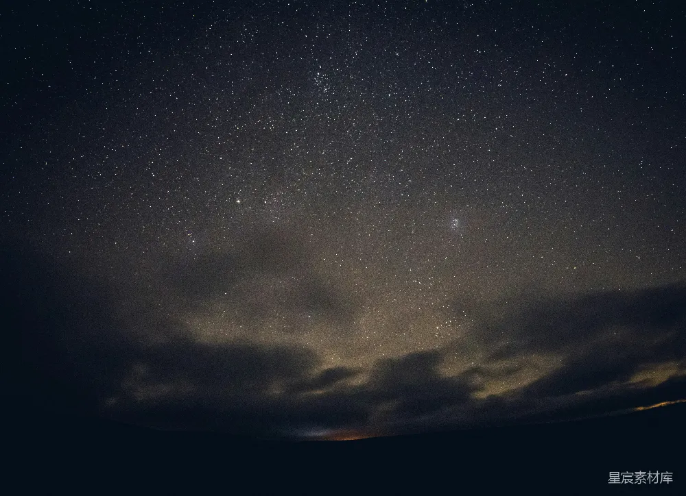 这张图片展示了夜空中繁星点点的银河，云层在黑暗中若隐若现，营造出一种宁静而神秘的氛围。银河的光辉在黑暗中显得格外耀眼，给人一种探索宇宙奥秘的感觉。适合用于自然风光、天文摄影或宁静氛围的场景。
