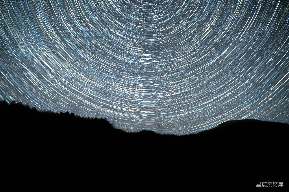 这张图片展示了夜空中星轨的美丽景象，星轨由长时间曝光捕捉到星星在夜空中移动的轨迹所形成。背景是深邃的夜空，前景是剪影般的山峦，营造出一种宁静而神秘的氛围。这种照片常用于天文摄影爱好者或自然风光的展示。
