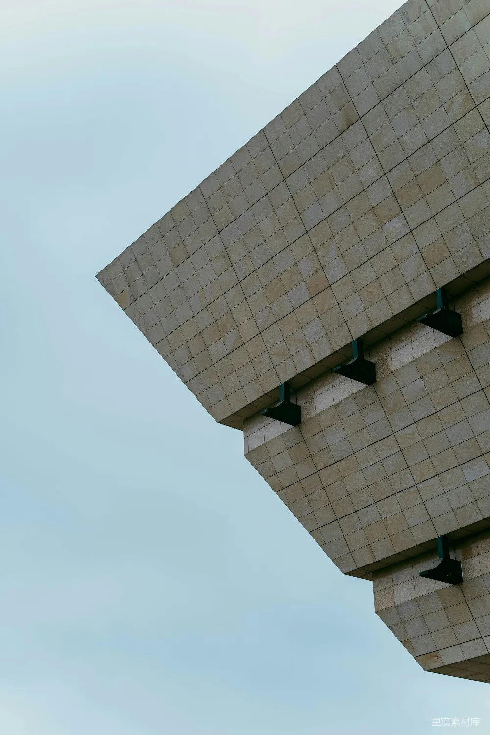 这是一张展示现代建筑几何美感的图片。照片中，建筑的结构线条简洁，采用了大量的方形元素，与背景的天空形成了鲜明的对比，展现出一种简约而富有力量的视觉效果。适合用于建筑设计、现代城市风貌展示或抽象艺术设计相关主题。