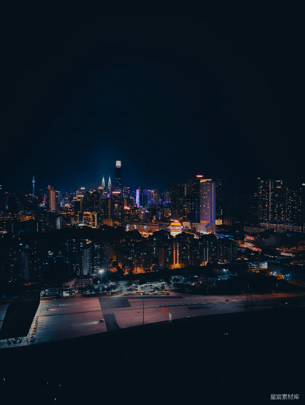 这张图片展示了夜晚的城市景色，高楼大厦灯火辉煌，街道上车辆行驶，形成一幅充满活力的现代都市夜景图。背景中可以隐约看到著名的地标建筑，夜色中展现出城市的繁华与现代感。适合用于城市旅游、夜间城市风光等场景。