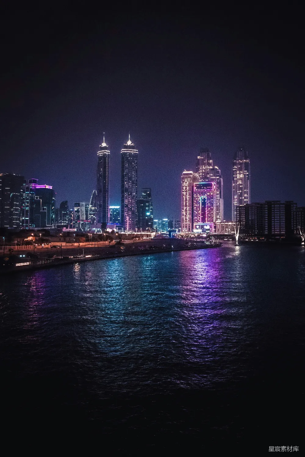 这张图片展示了一个城市的夜景，高楼大厦在夜空中闪烁着五彩缤纷的灯光，倒映在水面上，形成美丽的光影效果。水面上的倒影与城市的灯光交相辉映，营造出一种梦幻而宁静的氛围，适合用于旅游、城市风光和夜晚主题的背景图片。