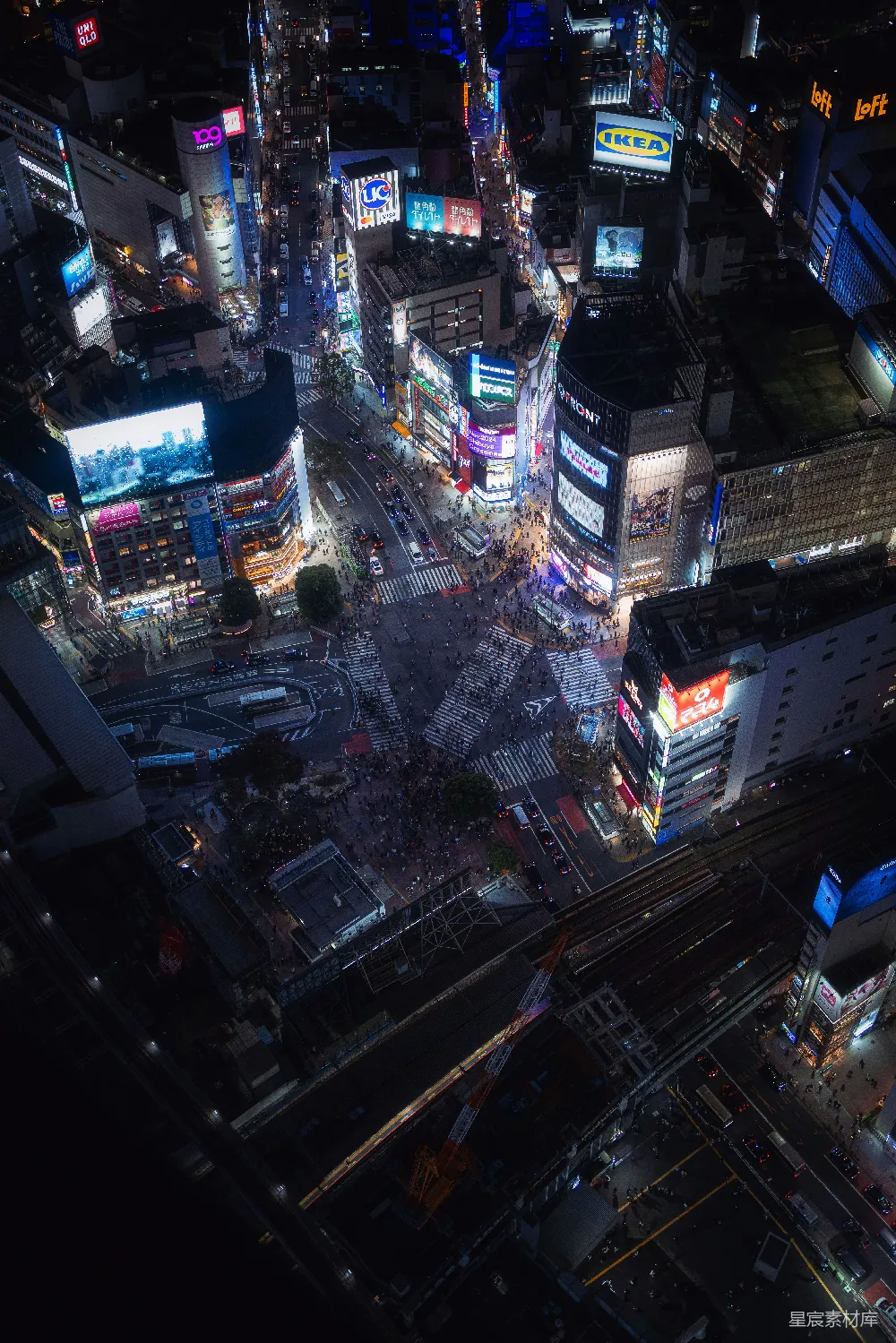 这张图片展示了夜晚城市的繁华景象。高楼大厦上灯火辉煌，街道上人来人往，车流不息，展现出都市的活力与繁忙。视角从高处俯瞰，给人一种宏大而细腻的感觉。适合用于描述城市夜景、都市生活或繁忙街道的主题。