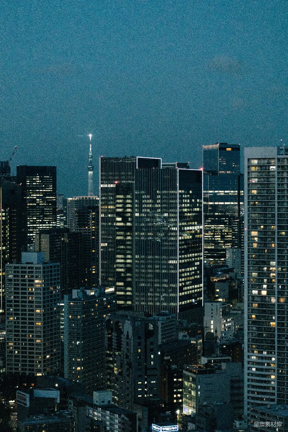 这张图片展示了夜晚的城市景象，高楼大厦的灯光在夜空中闪烁，展现出城市繁华与现代感。天空中隐约可见的天线塔进一步突显了城市的高度与现代化特征。适合用作城市夜景的背景或城市生活的主题图片。