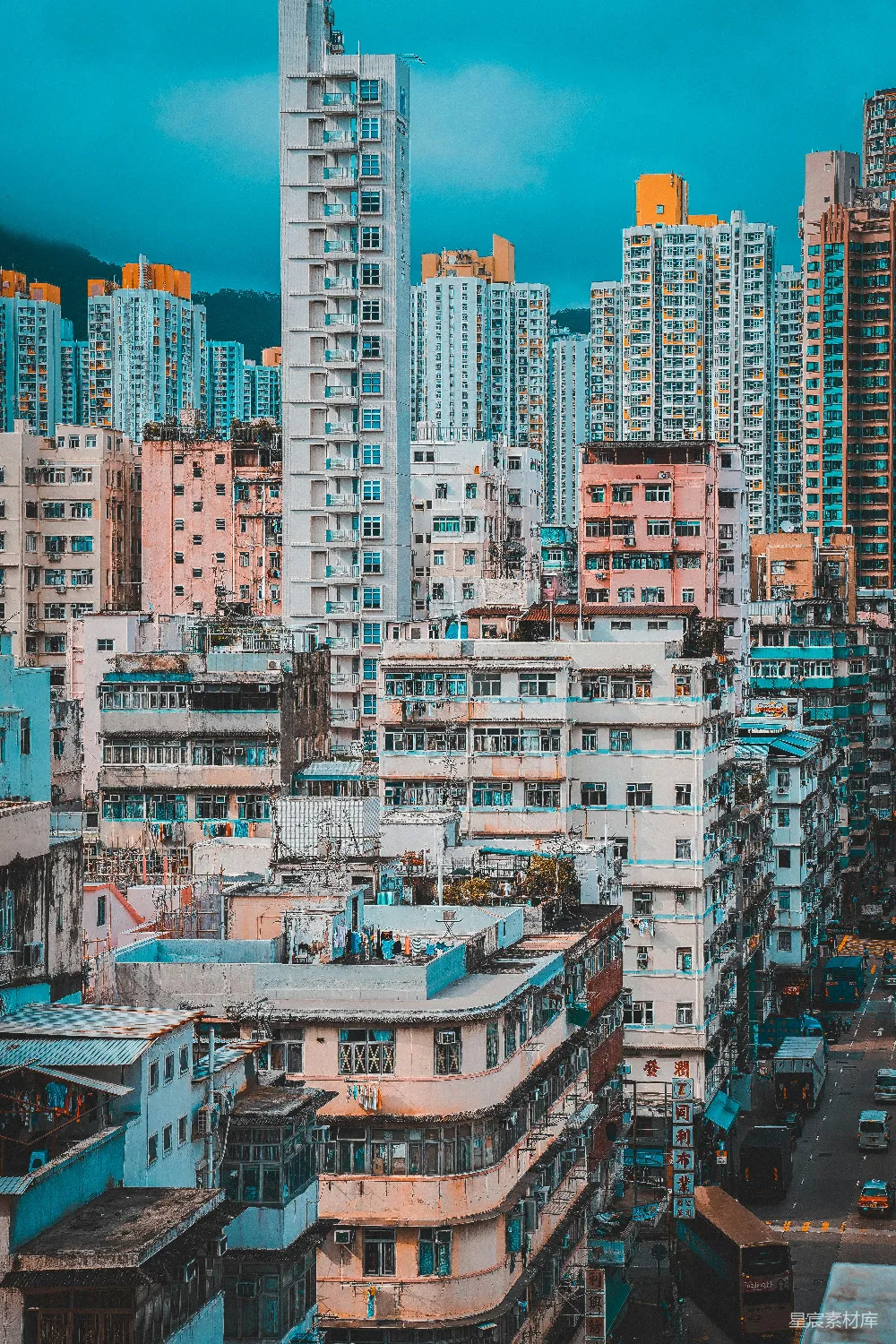 图片展示了一座城市的全景，高楼大厦错落有致，色彩丰富，建筑物之间点缀着绿色植物，呈现出一种充满活力的城市景象。天空呈现出深蓝色，给人一种宁静而充满希望的感觉。