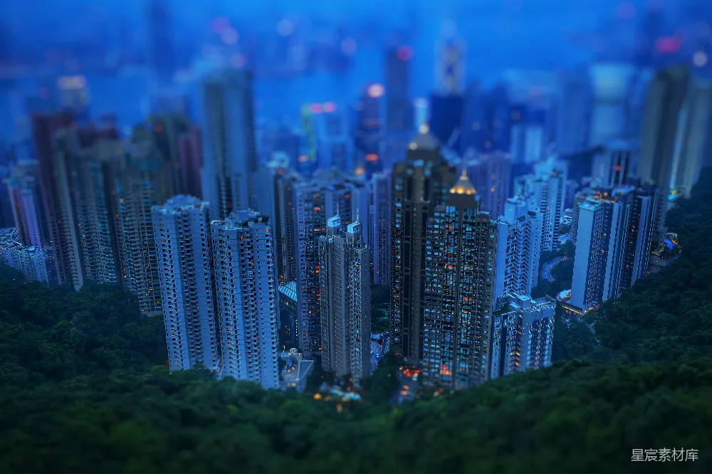 这张图片展示了夜晚城市中高楼大厦的微缩模型，使用了蓝色调，营造出一种梦幻般的氛围。高楼大厦林立，灯光点缀其间，周围环绕着郁郁葱葱的树木，给人一种繁华与自然共存的感觉。适合用于城市规划、建筑设计或微缩模型相关主题的展示。