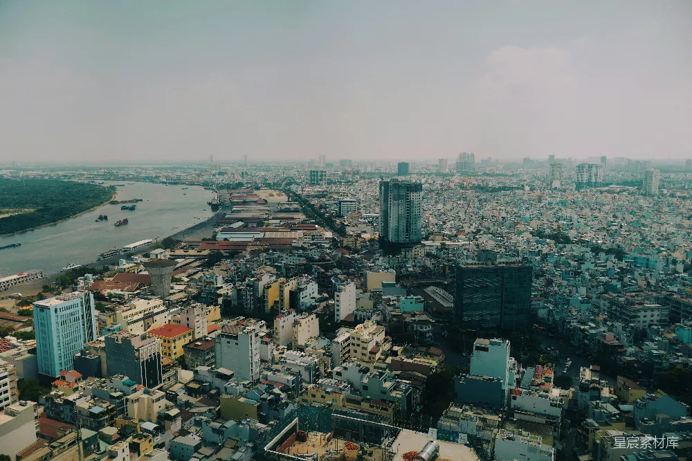 这张图片展示了城市与河流的全景俯瞰，画面中河岸两旁密集的建筑群错落有致，远处的高楼与近处的低矮建筑形成对比，展现出城市发展的多样性和复杂性。