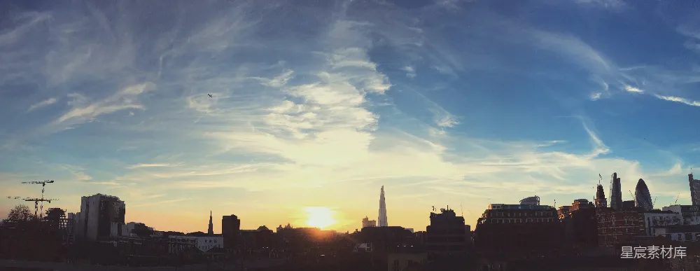 这张图片展示了伦敦的日落全景，天空中布满了细腻的云层，夕阳的余晖洒在城市的轮廓上，营造出一种宁静而美丽的氛围。适合用于城市风光、自然美景和旅行宣传。