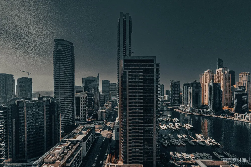 这张图片展示了现代都市夜景，高楼大厦林立，河流中停泊着许多船只。城市的灯光与天空的黑暗形成鲜明对比，营造出一种繁华而又宁静的氛围。适合用于城市风光、现代生活或都市夜景的主题设计。