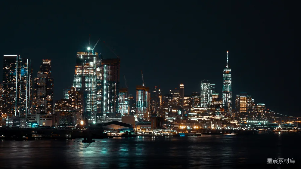 这张图片展示了纽约的夜景，灯光璀璨的城市天际线在夜幕下显得格外迷人。高楼大厦灯火辉煌，河流反射着城市的光芒，营造出一种繁华而宁静的氛围。适合用于城市风光、旅游宣传或夜景摄影的场景。