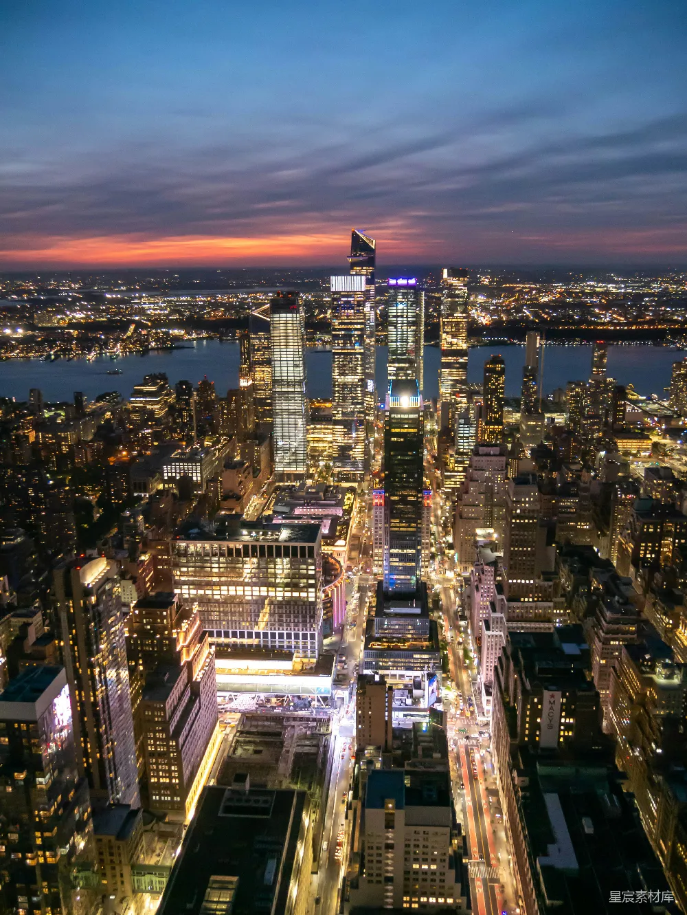 这张图片展示了纽约曼哈顿的夜景，高楼大厦灯火辉煌，街道上车流不息，远处的天际线与夜空交织出一幅壮丽的城市画卷。