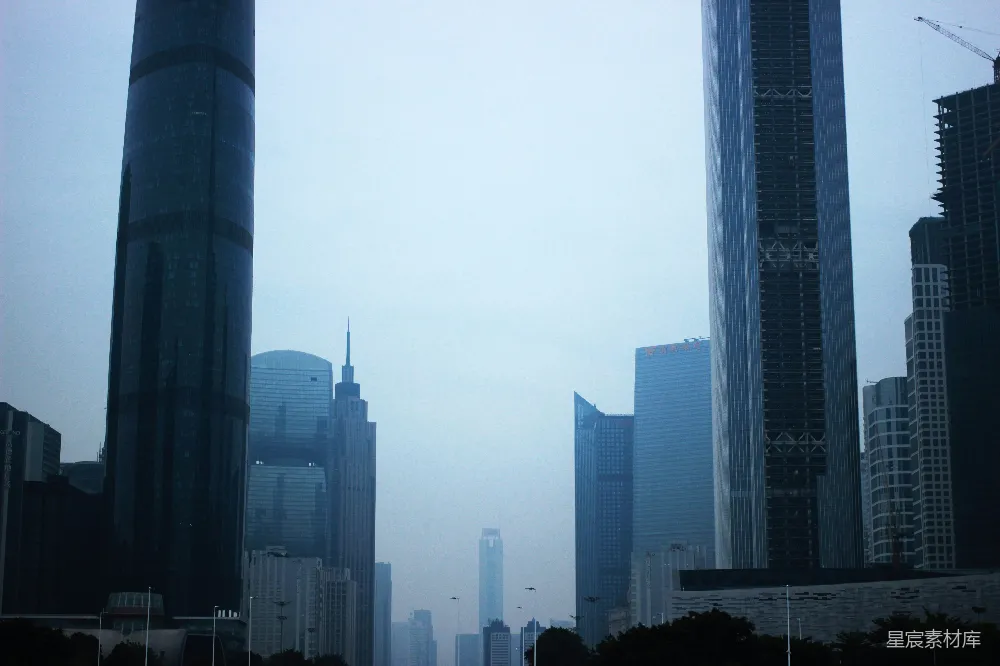 这张图片展示了城市中的摩天大楼在雾气中若隐若现的景象。天空被薄雾笼罩，使得建筑的轮廓显得朦胧而神秘。背景中的高楼大厦和近处的建筑在雾中形成了一种独特的视觉效果，营造出一种宁静而略带忧郁的氛围。适合用于表现城市现代化与自然环境交织的场景，或是