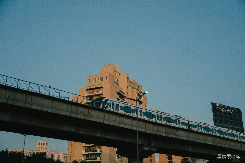 这张图片展示了城市中的现代地铁列车，它行驶在高架轨道上，背景是高楼大厦和蓝天。整个场景给人一种现代都市生活的氛围，强调了城市的繁荣与便利。图片色调柔和，适合用于展示城市交通、现代建筑或城市生活的主题。