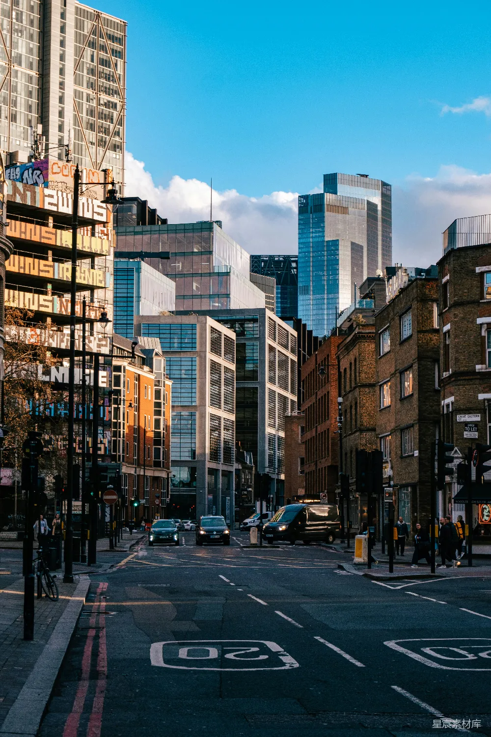 这张图片展示了一个现代化的城市街景，高楼大厦林立，街道整洁，车辆有序停放，天空湛蓝，云朵飘逸。整个场景充满了都市的活力与现代感，适合用于展示城市生活的主题。