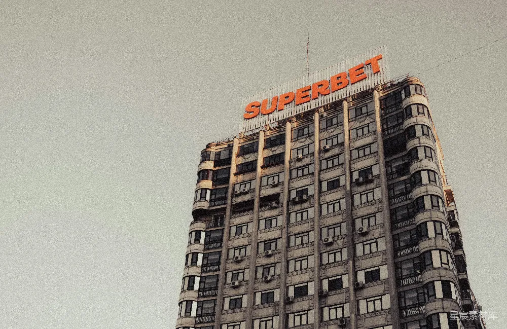 这张图片展示了一座高层建筑的侧面，建筑物上方醒目地展示着“Superbet”的大红标志。建筑物的外墙装饰简洁，窗户排列整齐，整体风格显得非常现代。天空背景显得阴沉，给人一种静谧而略带压抑的感觉。适合用于城市景观、商业宣传或建筑设计相关的内容