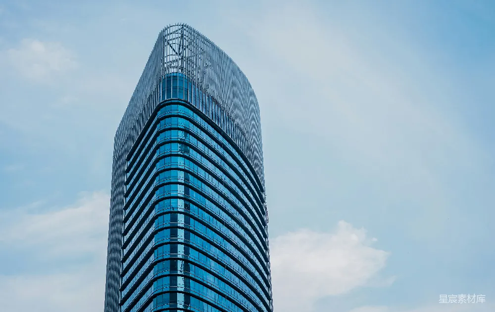 这是一张展示现代城市天际线的建筑照片。图片中，一座现代风格的高楼在蓝天白云的映衬下显得格外引人注目。高楼的玻璃幕墙反射出周围的环境，展现出城市的活力与繁华。适合用于城市规划、建筑设计、现代生活方式等主题的背景或封面设计。