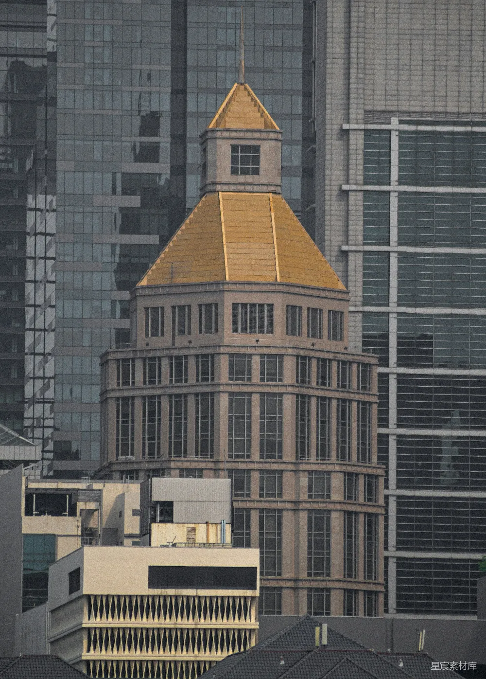 这张图片展示了一座独特的建筑，其顶部有一个金色的圆顶，与周围现代化的高楼大厦形成鲜明对比。建筑的圆弧形设计和金色的圆顶在灰色的天空下显得格外醒目。这些建筑位于一个繁忙的城市区域，周围是其他高大的玻璃幕墙大楼，体现了现代都市的景象。