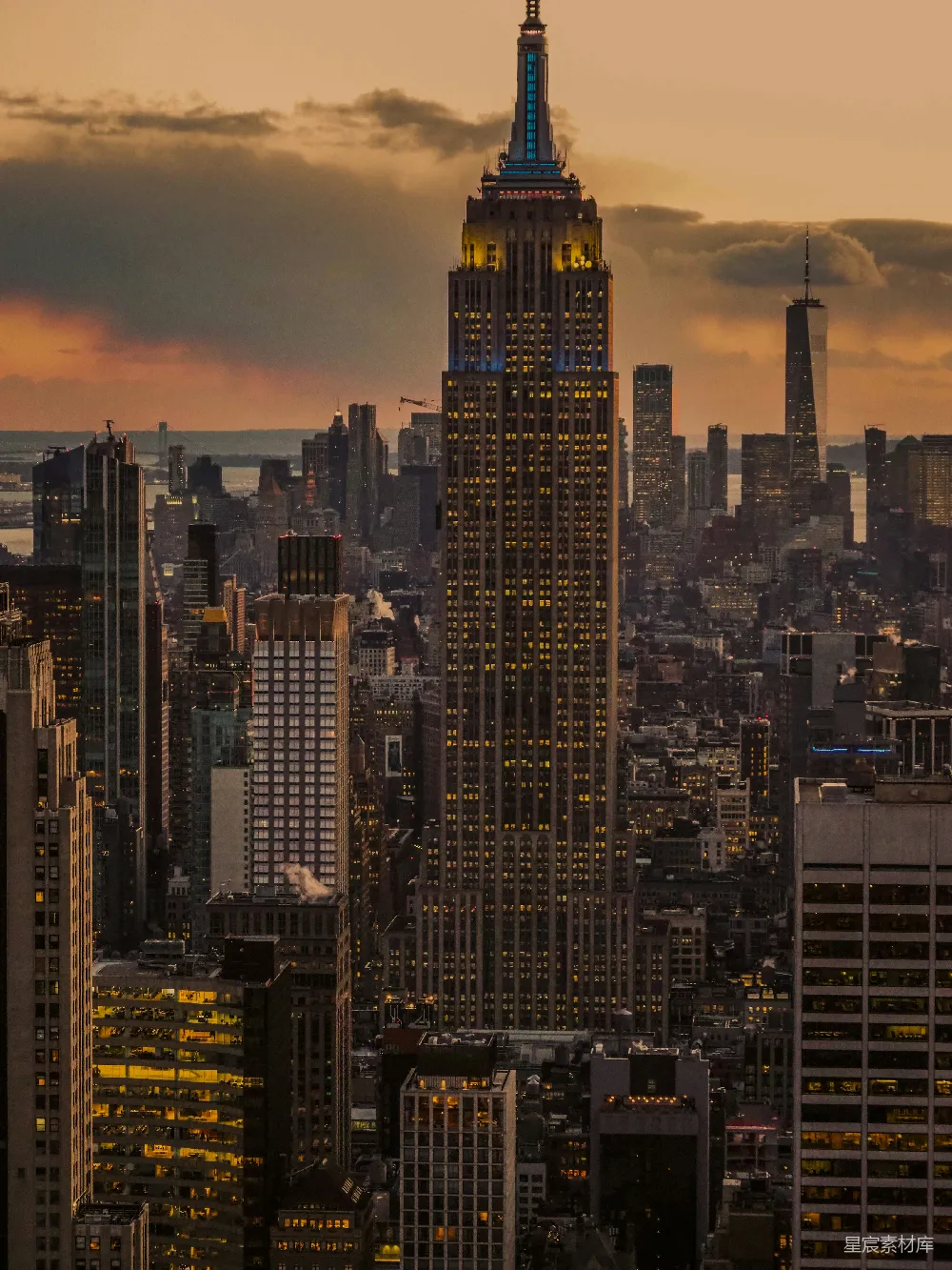 图片展示了纽约市的标志性建筑之一，帝国大厦在黄昏时分的美丽景象。灯光从底部到顶部渐变，与天空的橙色和紫色云层交相辉映，营造出一种宁静而壮丽的氛围。这座建筑在夜幕降临时显得格外耀眼，象征着城市的活力与魅力。