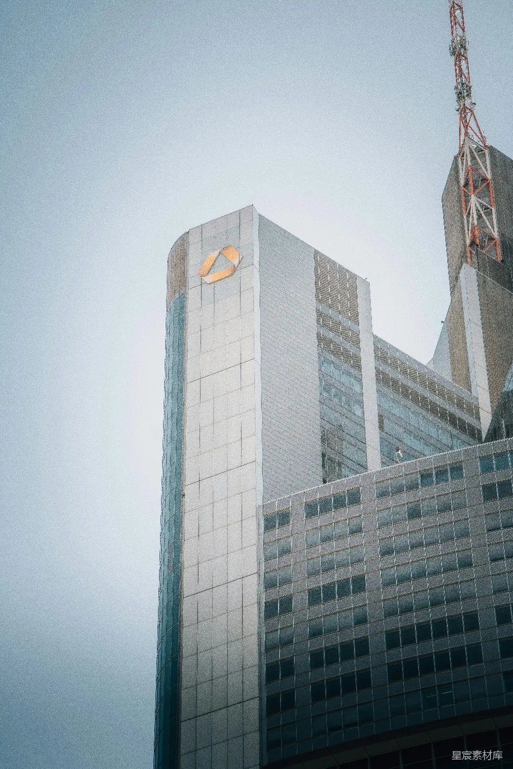 这张图片展示了现代化城市的标志性建筑——一座高耸的摩天大楼。大楼的玻璃幕墙在阳光下反射出耀眼的光芒，显示出其在城市景观中的重要地位。背景中的天线塔进一步强调了这些建筑物的现代感和都市气息。整体画面简洁而富有力量，适合用于城市风光、商务主题或