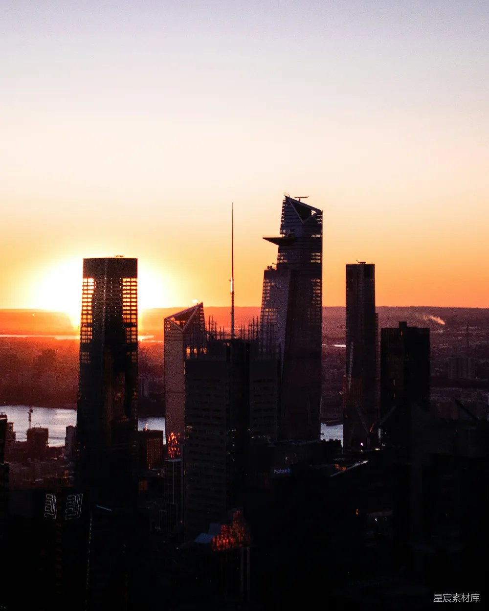 这张图片展示了城市中的高楼大厦在日落时的剪影，夕阳的余晖映照在建筑物上，形成美丽的橙色和金色，营造出一种宁静而美丽的城市黄昏景象。适合用于城市风光、建筑设计或自然风光的背景素材。