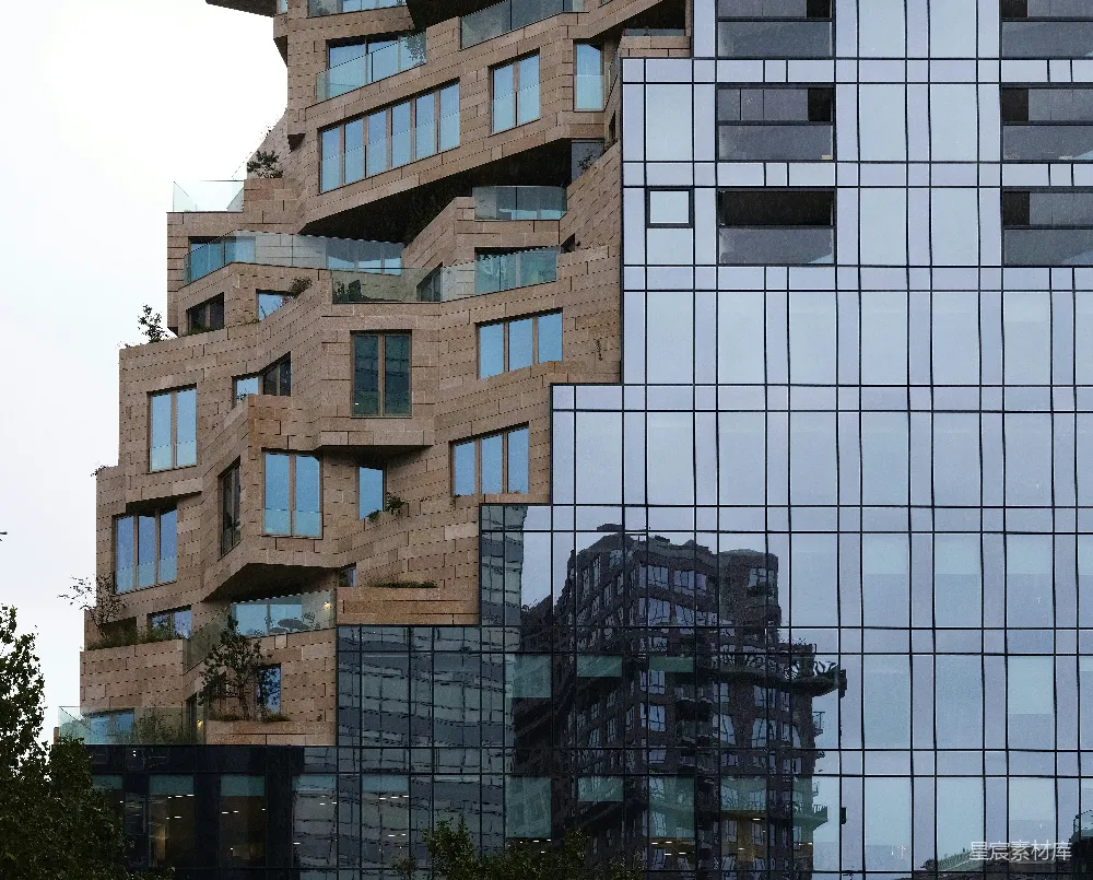 这张图片展示了现代建筑与自然的和谐共存。左侧的建筑以自然石材为特色，展示了与自然的亲和力，而右侧的玻璃幕墙则体现了现代城市的风貌。建筑结构错落有致，玻璃反射出周围的建筑和环境，营造出一种独特的视觉效果。这张图片适合用于城市设计、建筑美学和可
